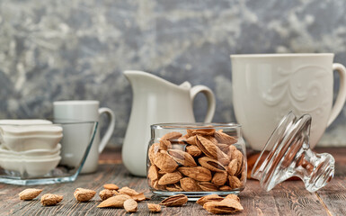 Almonds-nut kernels lie on wooden planks, against the background of glass dishes.