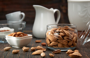 Almonds-nut kernels lie on wooden planks, against the background of glass dishes.