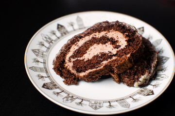 Swiss sponge cake with cream and chocolate on a white plate.