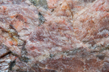 High granular texture of natural granite with color stains and small details on the surface in light blur with soft focus