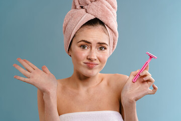 Woman in towel holding blade over blue wall background