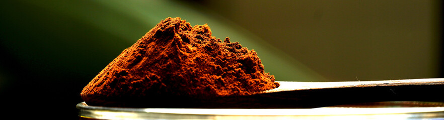 close up view of wooden spoon with cocoa powder with blurred background. chocolate concept