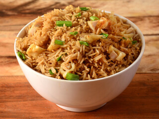 Indian cuisine Healthy and tasty chicken fried rice served in white bowl over a rustic wooden background, selective focus