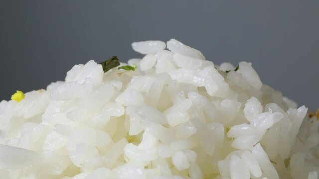 Sprinkling Wasabi furikake on top of Japanese white rice close up
