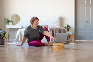 Senior woman is preparing for a home workout under the guidance of an online instructor.