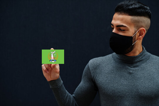 Egyptian man in gray turtleneck and black face protect mask show Monufia flag isolated background. Governorates of Egypt coronavirus concept.