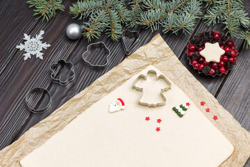 Dough for baking cookies on paper with cookie cutter molds and Christmas decorations