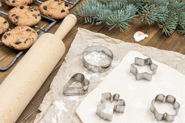 Making Christmas cookies. Cookie cutter molds on dough. Ready-made cookies and fir branches