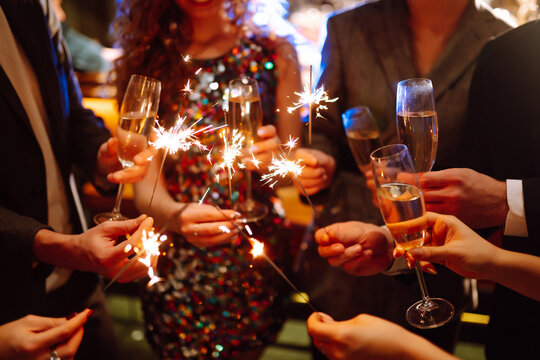 Glowing Sparkles In Hands. Group Of Happy People Enjoying Party With Fireworks. Winter Holiday, Youth, Lifestyle Concept.