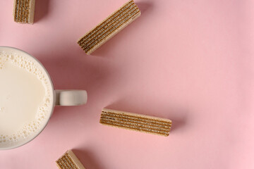 Chocolate waffles and a mug of milk on a pink background