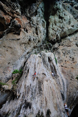 Rock climber ascends limestone wall at Railay Beach, Krabi, Thailand.