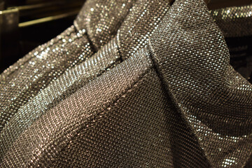 Lots of silver sequins on dresses on hangers in the store. Trendy festive clothes for New Year and Christmas.