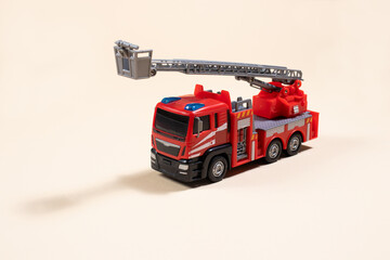 Toy typewriter on beige background red fire truck made of plastic. For the toy store, a gift for the boy