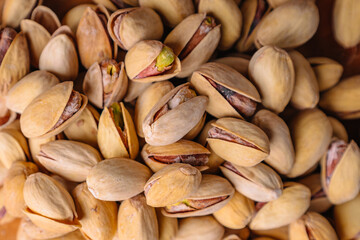 Green fresh pistachios as texture on wooden background
