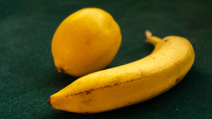 banana and lemon on emerald background, healthy food