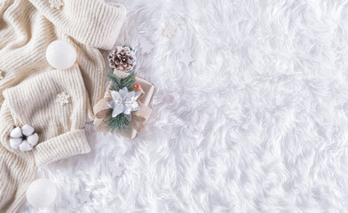 Obraz na płótnie Canvas Winter cozy background with cup of coffee, warm sweater, gift box, cotton flower and christmas ball on wool carpet background, Top view with copy space.