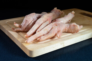 Chicken paws on wooden board on table