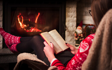 Girl reading by the fire. Cozy winter lifestyle