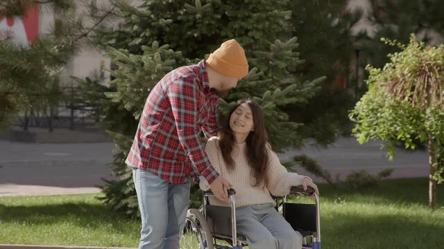 Portrait of disabled happy young woman n wheelchair and her husband looking at camera. Asian handicapped girl with paralysis living full life. Couple in love. 6k downscale 10 bit color.