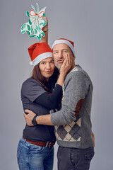 Middle-aged happy couple holding a paper concept mistletoe and looking very loved celebrating for christmas