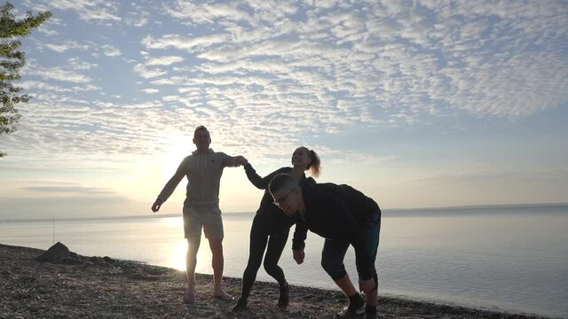 Friends are jumping against the background of dawn and the lake.