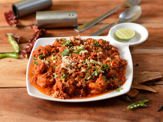 Delicious spicy prawns masala or shrimp curry cooked in south indian style.. served over a rustic wooden background, selective focus
