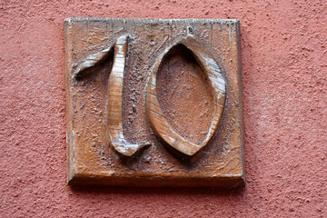 Braunes Hausnummernschild Nummer Zehn auf rötlicher Hauswand, Deutschland, Europa
