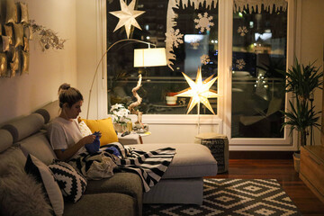 Young woman knitting on the sofa at christmas time