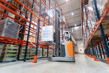 Forklift standing under tall shelves in large warehouse