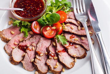 Roasted duck with cherry tomatoes and salad marinated in red wine on a plate