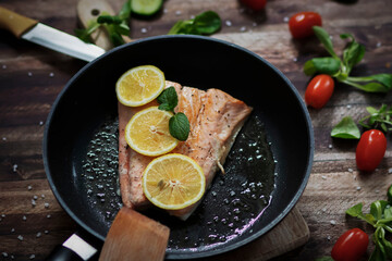 Salmon in a pan with lemon and other vegetables. Salmon on plates