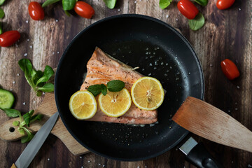 Salmon in a pan with lemon and other vegetables. Salmon on plates