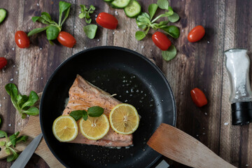 Salmon in a pan with lemon and other vegetables. Salmon on plates
