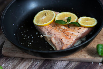 Salmon in a pan with lemon and other vegetables. Salmon on plates