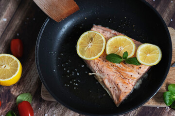 Salmon in a pan with lemon and other vegetables. Salmon on plates