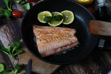 Salmon in a pan with lemon and other vegetables. Salmon on plates