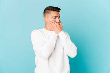 Young caucasian handsome man isolated thoughtful looking to a copy space covering mouth with hand.