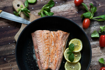 Salmon in a pan with lemon and other vegetables. Salmon on plates