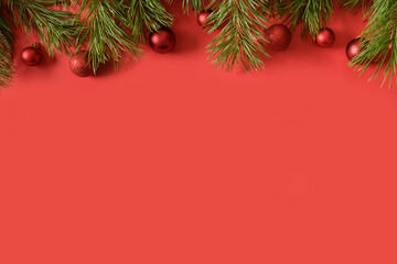 Christmas banner with red decor and evergreen fir branches on red background. Top view. Xmas greeting card.