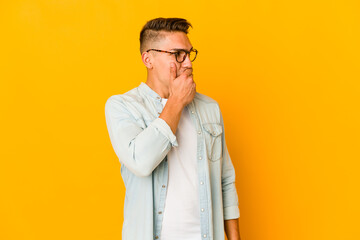 Young handsome caucasian man isolated thoughtful looking to a copy space covering mouth with hand.