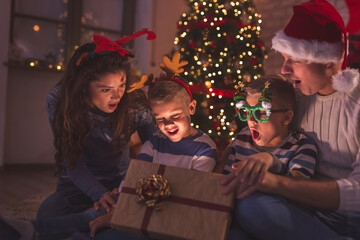 Family opening magical glowing Christmas present