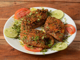Delicious crispy King fish fry also known as indian surmai, served with onion and lemon placed over a rustic wooden background,selective focus
