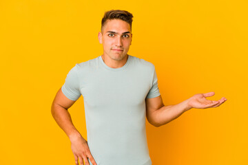 Young handsome caucasian man isolated doubting and shrugging shoulders in questioning gesture.