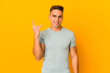 Young handsome caucasian man isolated showing a horns gesture as a revolution concept.