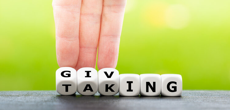 Hand turns dice and changes the word taking to giving.