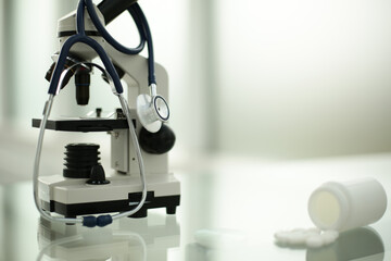 Stethoscope microscope and pills on glass table