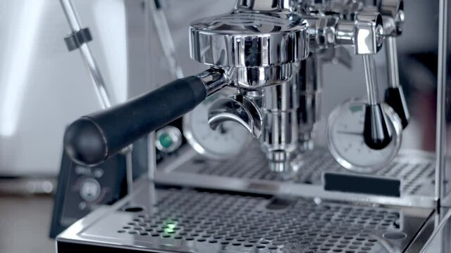 Professional one group metallic steel coffee machine. Female barista hand inserting double portafilter to make coffee. High quality video 4k still footage.