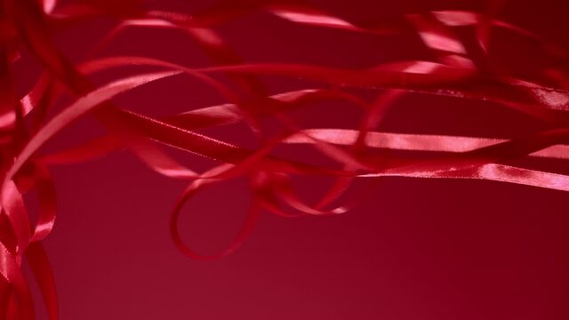 Deep ruby colored chiffon strips are dropping down on a velvety cherry red background. Vertical shot. Atmospheric video background. New year, Christmas festive mood 4k still high quality video footage