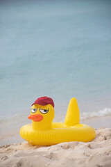 
INFLATABLE YELLOW LIFE DUCK WITH A RED BASEBALL CAP ON THE SHORES OF A VIRGIN CARIBBEAN TROPICAL BEACH