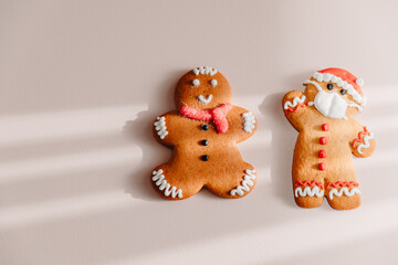 Two different gingerbread cookies: one with the image of a protective mask, and the other without it. The concept of conscious and safe celebration of Christmas and New Year